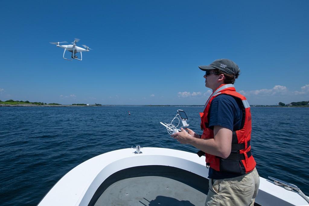 A student in a boat flying a drone over the water