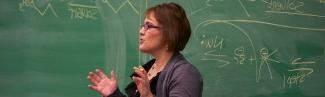 A faculty member stands in front of a chalkboard